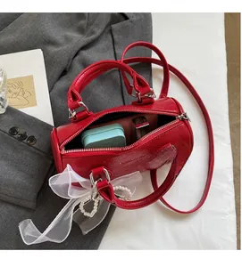 Détail de l'intérieur du sac seau rouge montrant les essentiels et le nœud en dentelle
