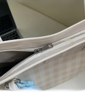 Detail of smooth metal zipper and internal pocket on checkerboard tote bag