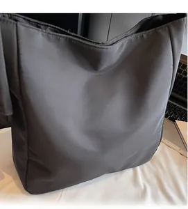 Detail view of smooth black nylon fabric on a soft slouchy tote bag for daily commute