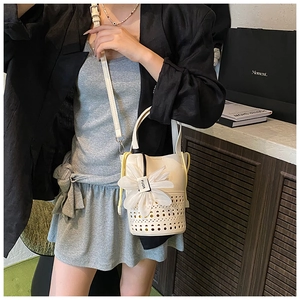 Détail du sac seau en cuir blanc avec découpes laser et fleur en organza 3D élégante