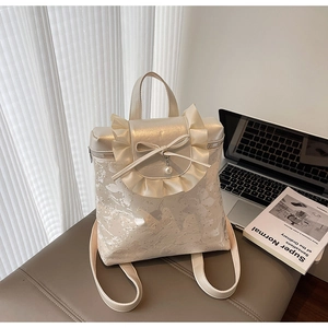 Detail of cream bow bucket bag with pearl pendant near laptop and book setup