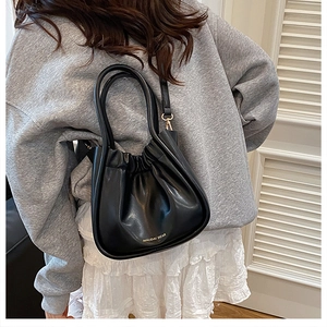 Detailed view of black pleated cloud bag with gold MAIDAI BEAR text and round handle