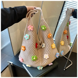 Vue macro d'un sac cabas en maille beige avec fleurs 3D colorées et anses souples