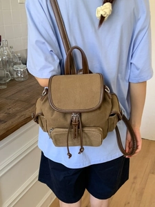 Vintage brown canvas backpack with leather trim shown on model in home kitchen setting