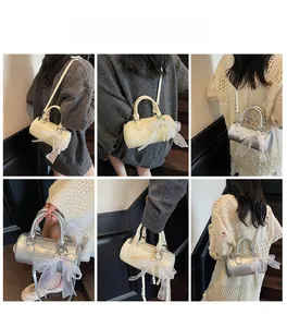 Détail d'un mini sac cylindrique avec nœud en dentelle et perles en argent et beige