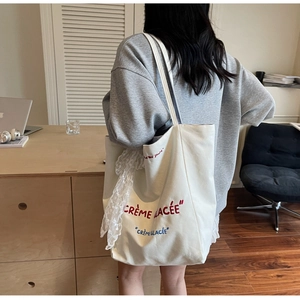 Detailed view of white canvas tote bag with French embroidery and lace ribbon scarf