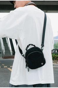 Détail d'un sac bandoulière en nylon noir imperméable avec poignée tressée et logo