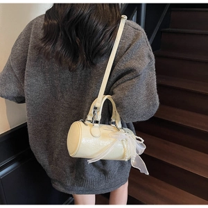 Vue arrière du sac seau cylindrique blanc crème avec nœud en dentelle perlée et bandoulière