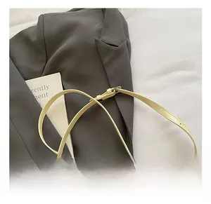 Detail of adjustable pale yellow leather strap with metal buckle on grey blazer