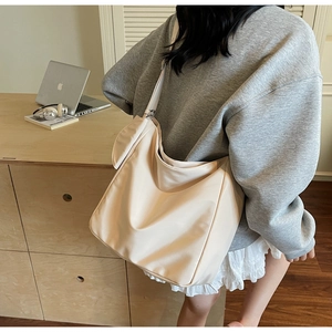 Detailed side view of off-white oversized hobo tote bag worn by a model in a cozy room