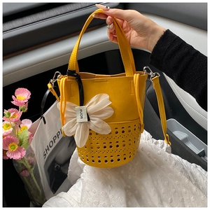 Détail du sac seau jaune ajouré avec pendentif fleur et motifs découpés au laser
