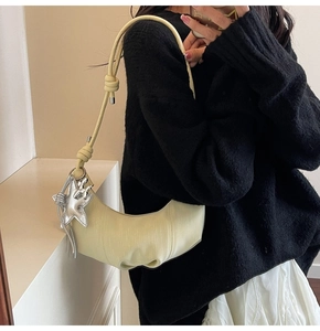 Detail of pale yellow crescent bag with knotted strap and silver star charm detail