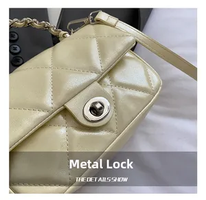 Detailed macro view of the silver metal swivel lock and quilted leather on the beige bag
