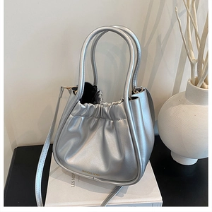Detail view of the silver metallic bucket bag featuring pleated design and top handles