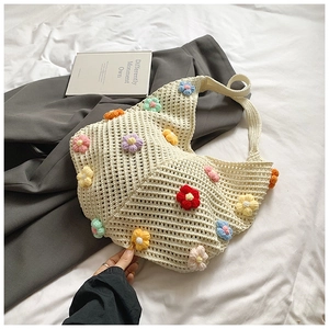 Détail d'un sac cabas en tricot crème avec fleurs 3D colorées et texture tissée douce