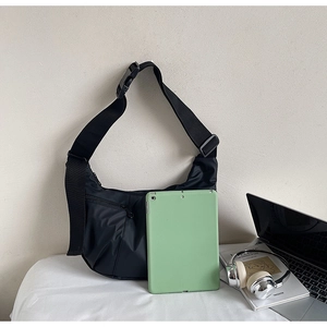 Detail view of large black nylon crescent crossbody bag showing spacious capacity and iPad fit