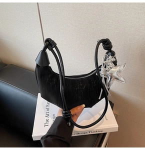 Detail of black crescent hobo bag with pleated texture and silver star charm