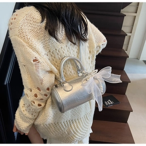 Détail du sac Boston argenté avec nœud en dentelle et chaîne perlée sur une personne