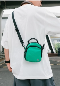 Vue de rue extérieure d'un sac bandoulière en nylon vert fluo imperméable sur t-shirt blanc