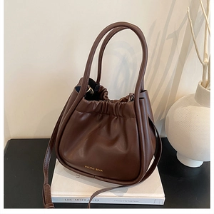 Detail of brown pleated drawstring bucket bag with handle and gold letter branding