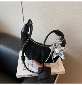 Detail of black crescent bag with vertical pleats and star balloon dog charms