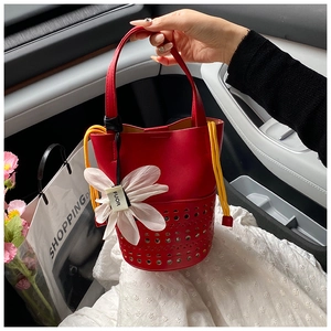 Détail du sac seau rouge ajouré en cuir avec cordon jaune et pendentif fleurie