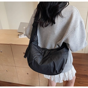 Close-up of black nylon crescent crossbody bag featuring dual exterior zipper pockets