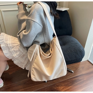 Chic beige nylon hobo bag featuring wide straps shown on model in a casual indoor setting