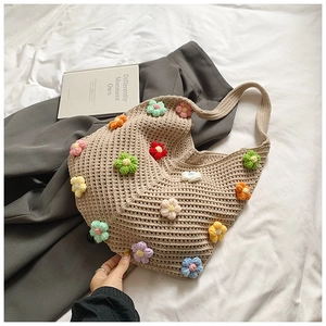 Détail d'un cabas en tricot beige avec fleurs au crochet colorées et texture douce