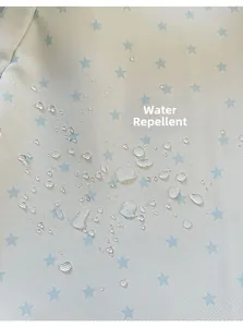Close-up of water-repellent off-white fabric with blue stars and clear water droplets