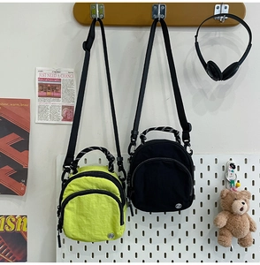 Gros plan de sacs bandoulière légers en nylon imperméable en jaune néon et noir classique
