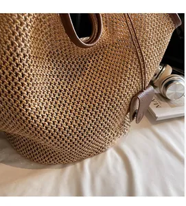 Close-up of woven straw tote bag texture with brown leather handles and casual style