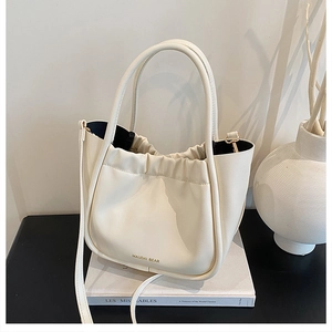 Close-up of cream white pleated bucket bag with gold lettering on elegant book