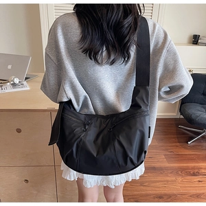 Detailed side view of a black crescent crossbody bag with double front zippers