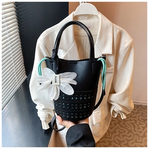 Détail du sac seau noir ajouré au laser avec cordon vert menthe et pendentif fleur
