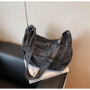 Detail of dark grey washed denim bag showing vintage multi-zipper pockets and fabric strap