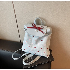 Detail view of light blue mini backpack featuring red bows on a black book