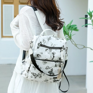 Detail shot of a white butterfly print backpack with black contrast straps on a model