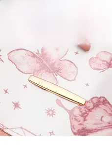 Détail macro de l'imprimé papillon rose et de l'ornement doré sur le sac à dos beige