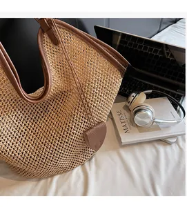 Detailed close-up of straw woven tote bag with leather handles and decorative leaf charm