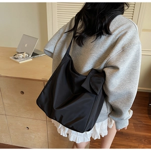 Detail view of a black oversized ruched nylon tote bag with wide strap in a home setting