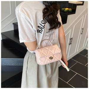 Pink quilted crossbody bag with golden chain handle and round metal clasp on female model