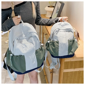 Detail view of two color-block nylon backpacks in navy, olive green and grey