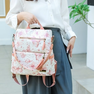 Close-up of stylish backpack with pink butterfly prints and decorative side tassel