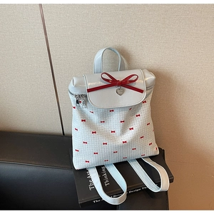 Close-up of light blue backpack with red bow prints and a heart-shaped metal pendant