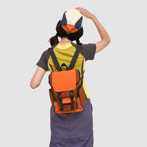 Rear view of model wearing a contrast color nylon backpack in orange and brown tones