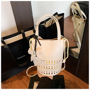 Gros plan du sac seau évidé blanc avec doublure jaune à cordon et pendentif fleur