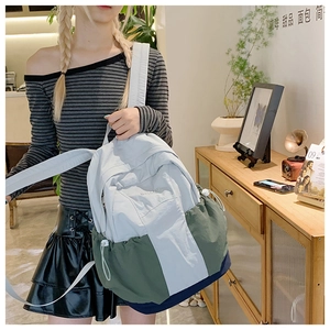 Detail of color-block nylon backpack with side drawstring pocket and brand logo