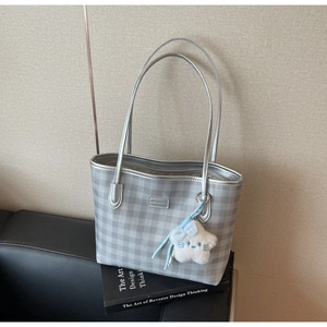 Detail of silver checkered tote bag featuring a plush star charm on a design book
