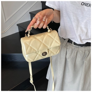 Detail of quilted crossbody bag featuring a metal twist lock and gold chain handle